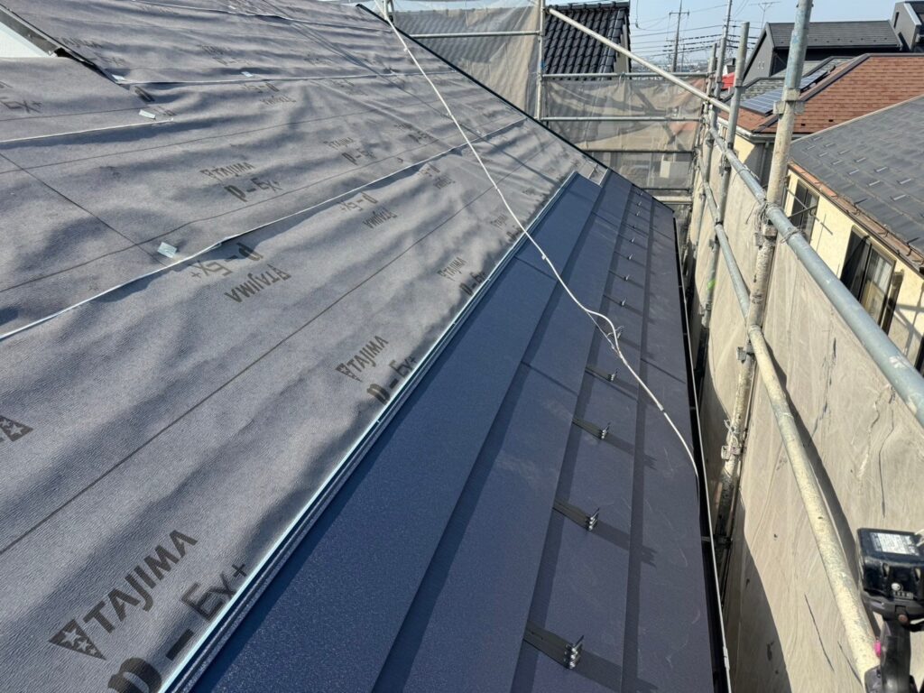 スーパーガルテクト(シェイドブルー)を貼り付ける屋根カバー工法の様子