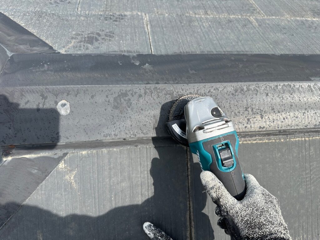 さいたま市の屋根塗装工事で棟板金のケレン掛けを実施。サビや汚れを丁寧に除去し、塗料の密着を高める下地処理。GAINA(ガイナ)N-40仕上げ予定。