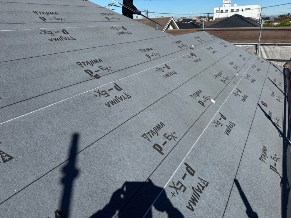屋根に防水シートを隙間なく貼り付け、雨漏り防止性能を強化している作業写真