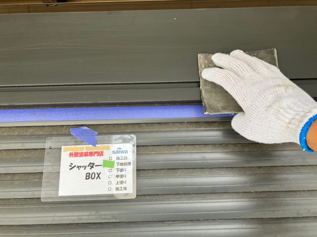 資格保有職人がシャッターボックスのサビや旧塗膜を丁寧にケレン掛けしている様子