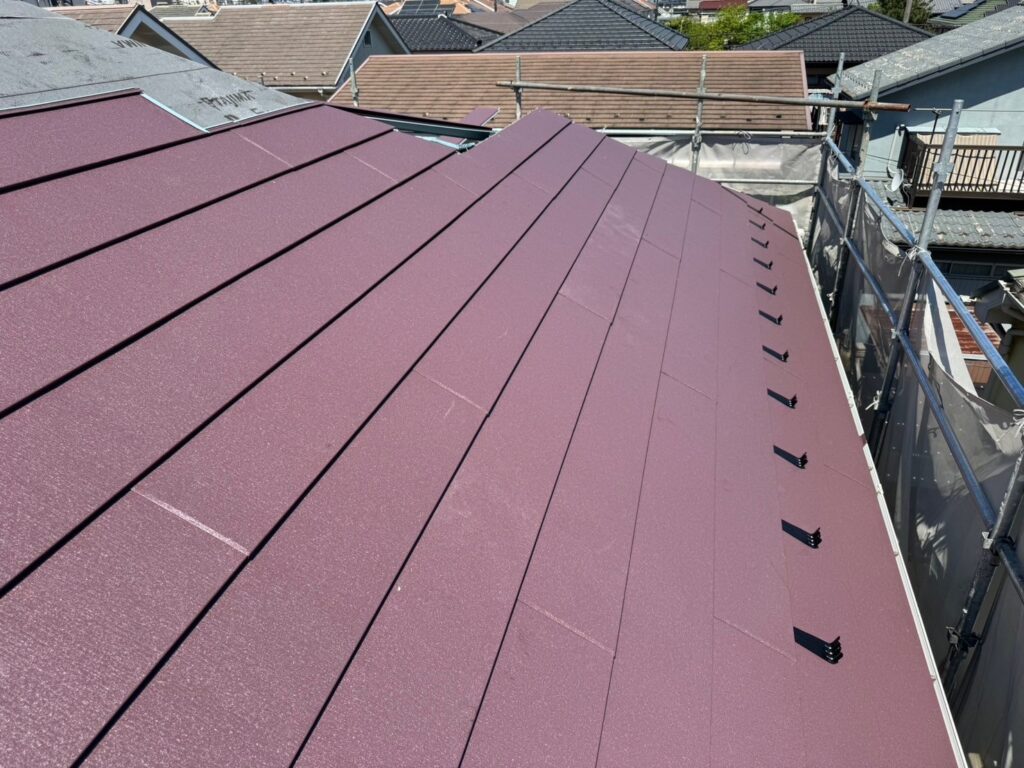 スーパーガルテクト(シェイドワインレッド)を屋根に取り付けている施工写真。高耐久金属材で防水性を向上
